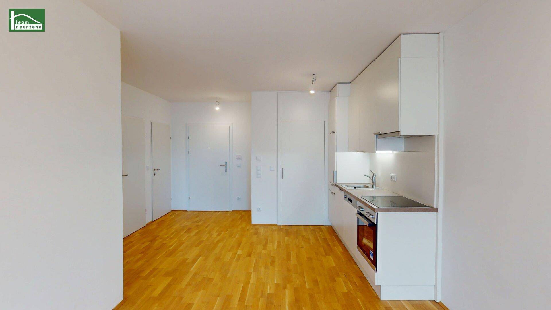 Kompakte, moderne Küchenzeile mit integrierten Geräten und hellem Parkettboden.