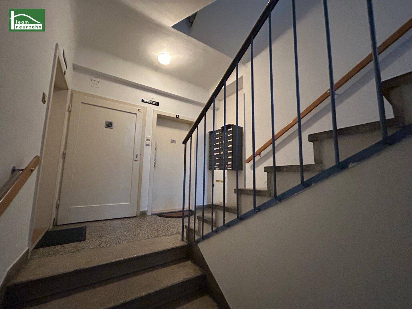Treppenhaus mit Geländer, Briefkästen und Zugang zu den einzelnen Wohneinheiten im Gebäude.