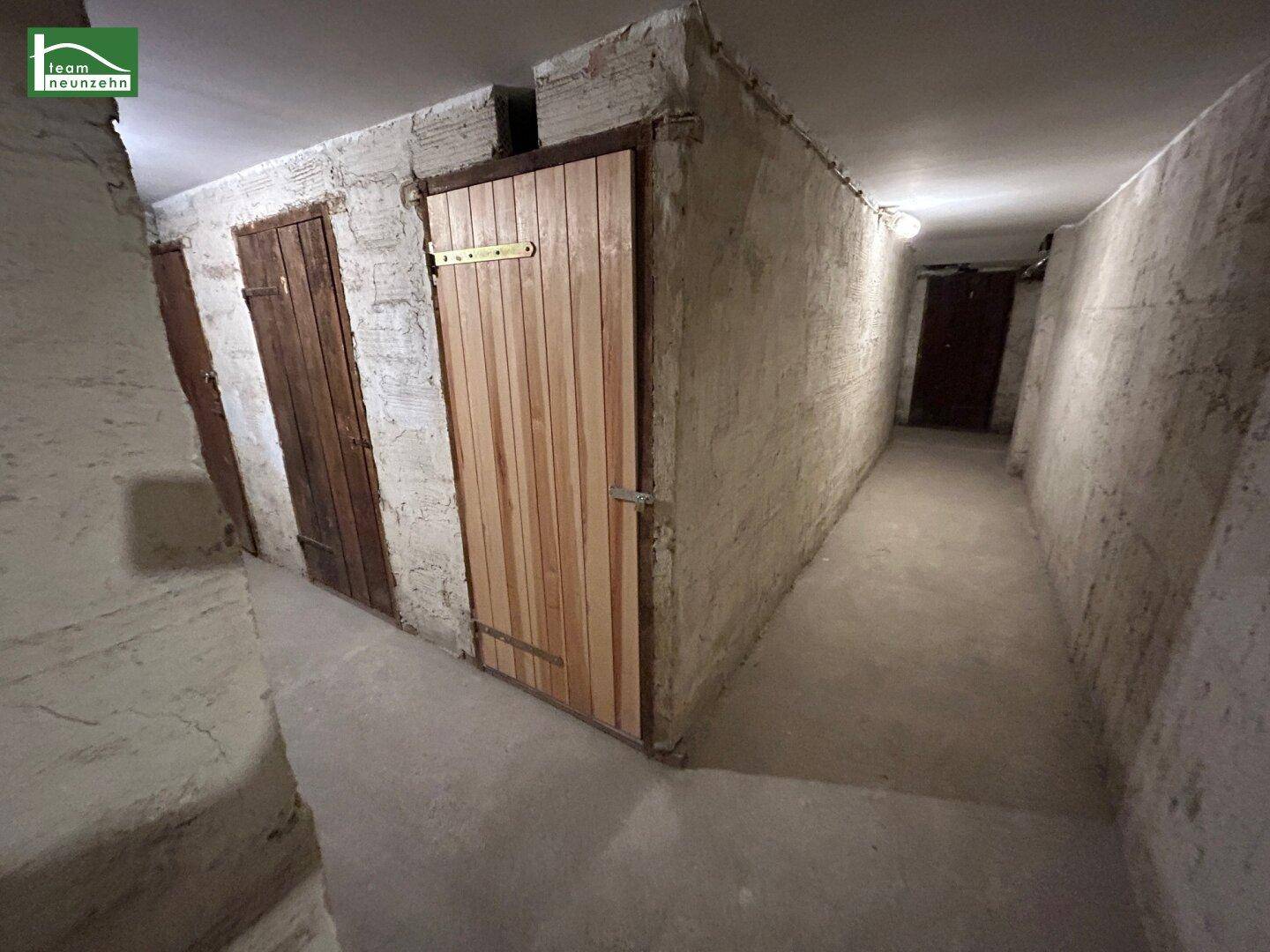 Kellergang mit mehreren Lagerräumen und robusten Holztüren, ideal für zusätzlichen Stauraum.