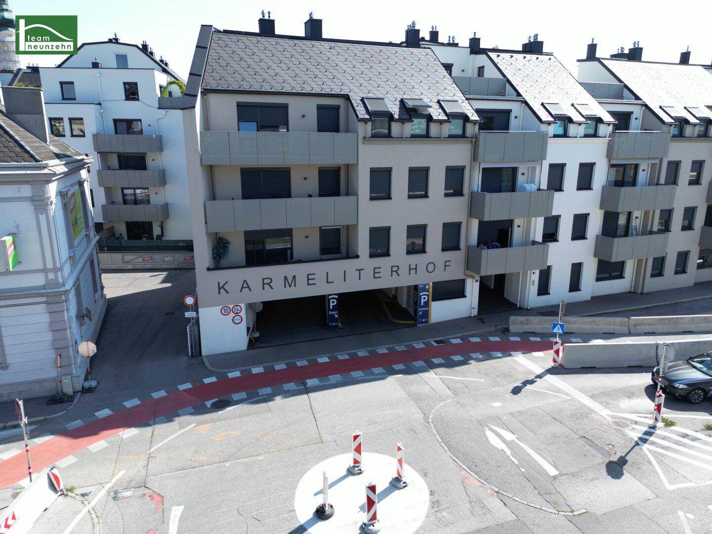 Eingangsbereich des Karmeliterhofs mit Zufahrt zur Tiefgarage und moderner Fassadengestaltung.