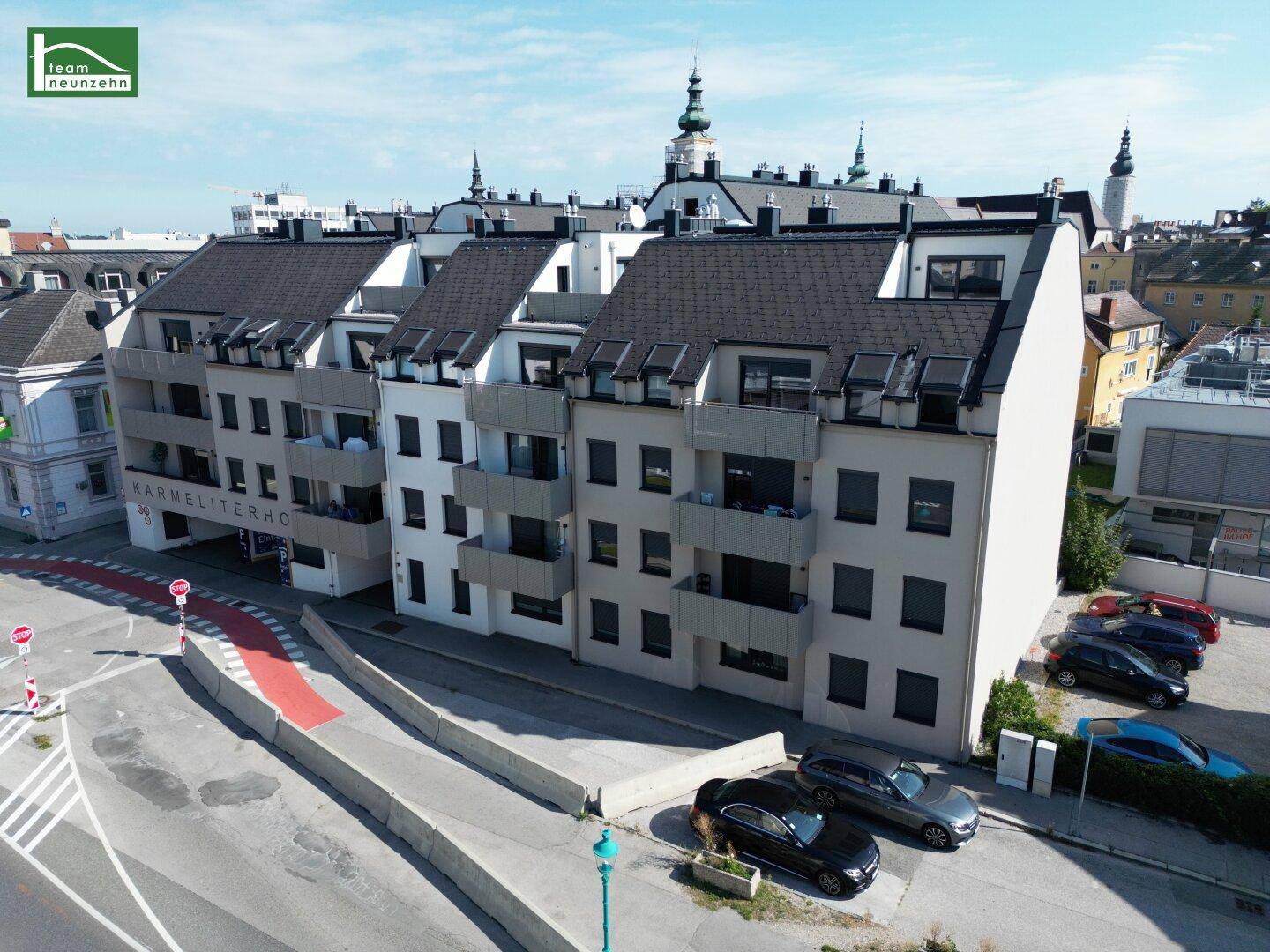 Moderne Wohnanlage mit dunklen Dächern, Balkonen und Zufahrt zur Tiefgarage.