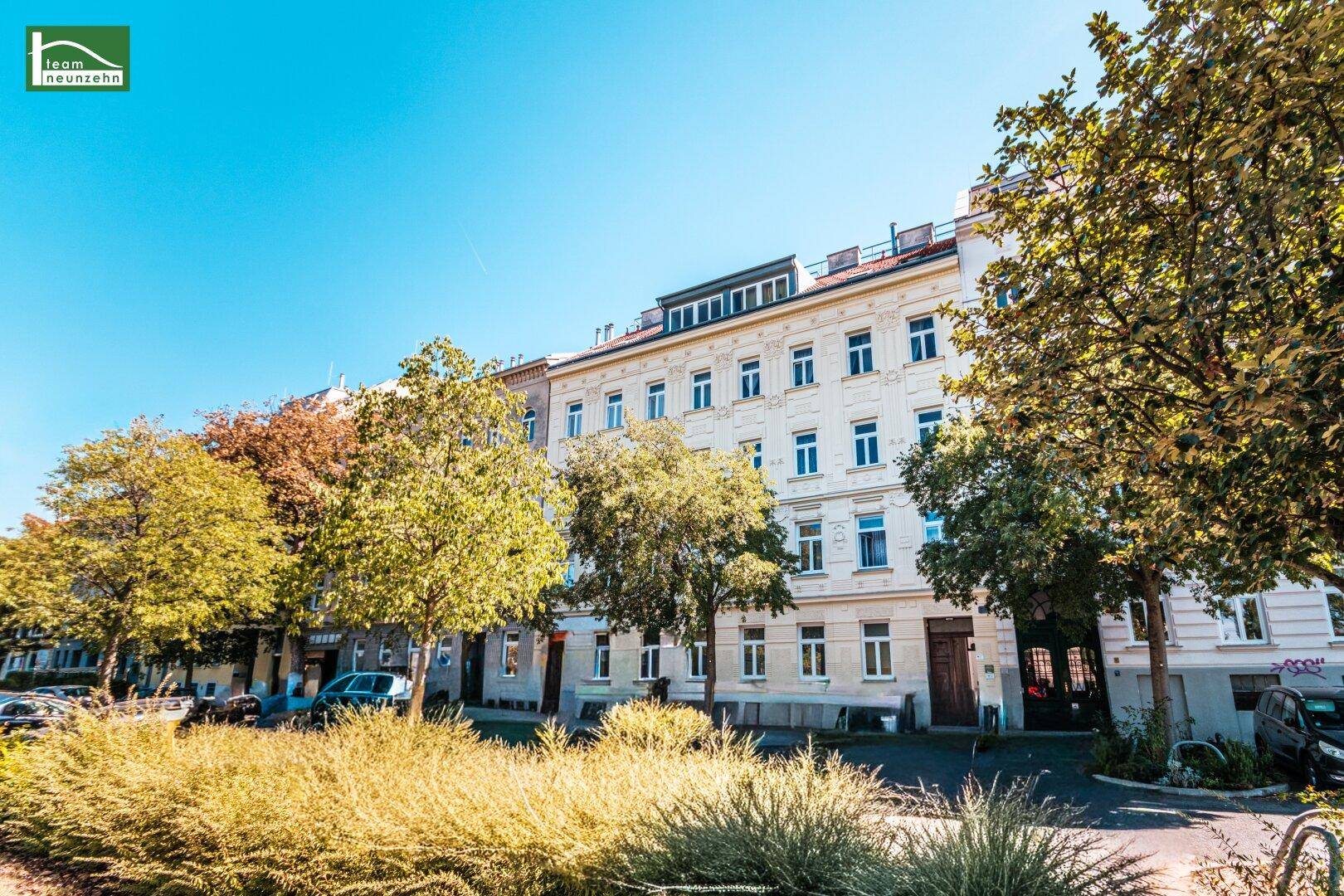 Attraktives Wohngebäude mit heller Fassade und gepflegter Umgebung, umgeben von Grünflächen.