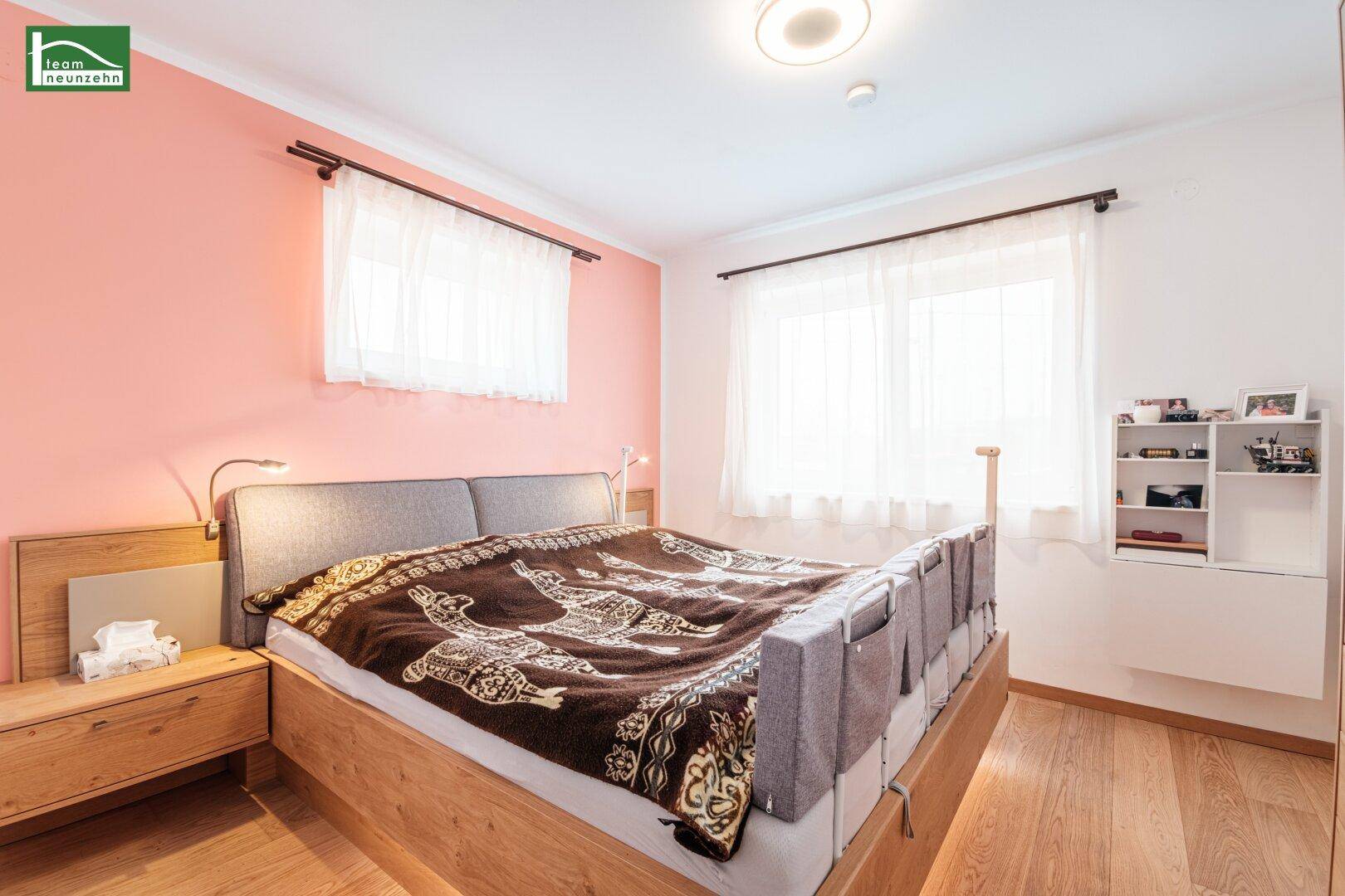 Gemütliches Schlafzimmer mit Holzbett, Nachttischen und großen Fenstern für viel Licht.