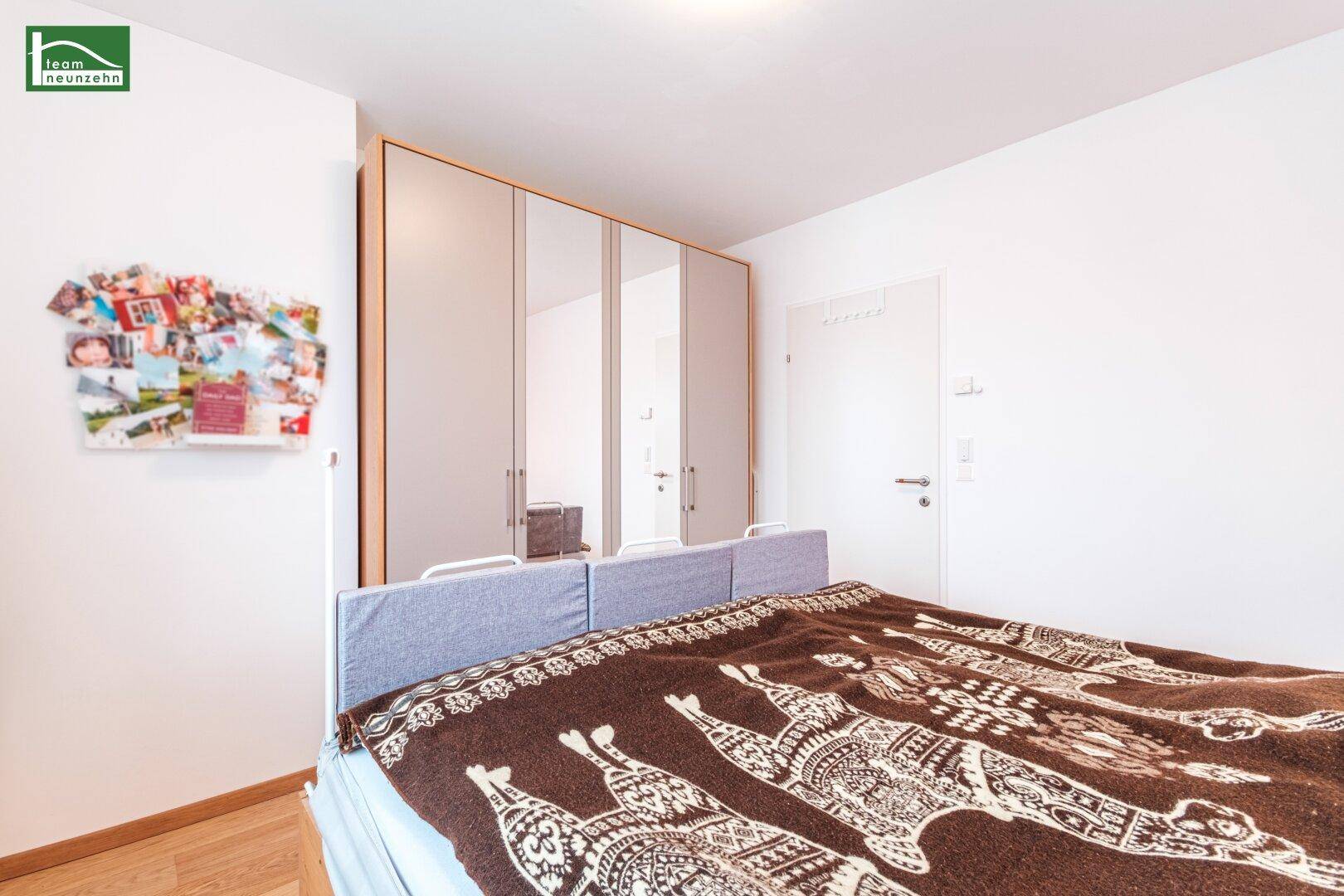 Schlafzimmer mit Holzboden und einem großen Spiegelschrank, der den Raum optisch vergrößert.