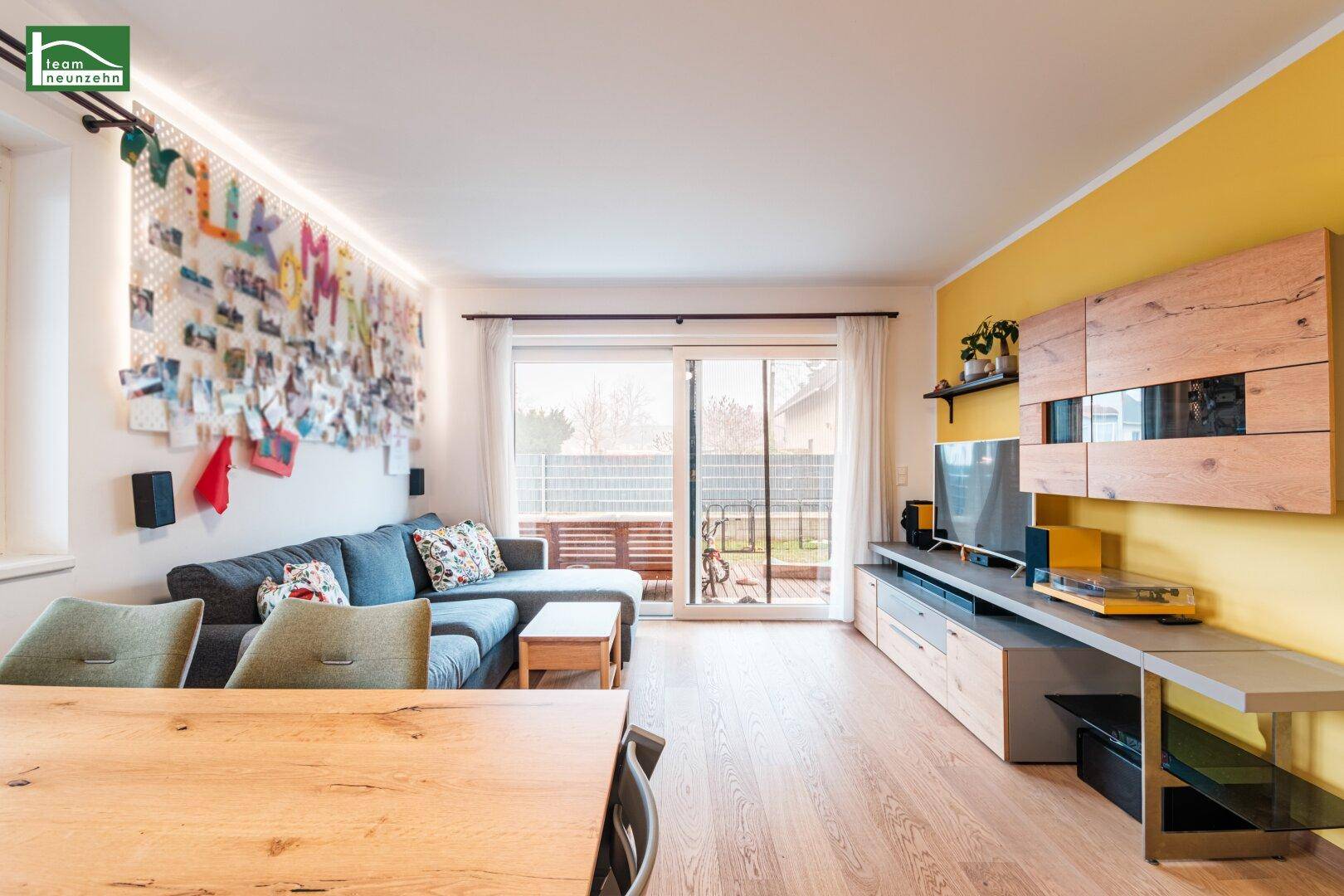 Geräumiger Wohnbereich mit Holzboden, gemütlichem Sofa und Zugang zu einem Außenbereich.
