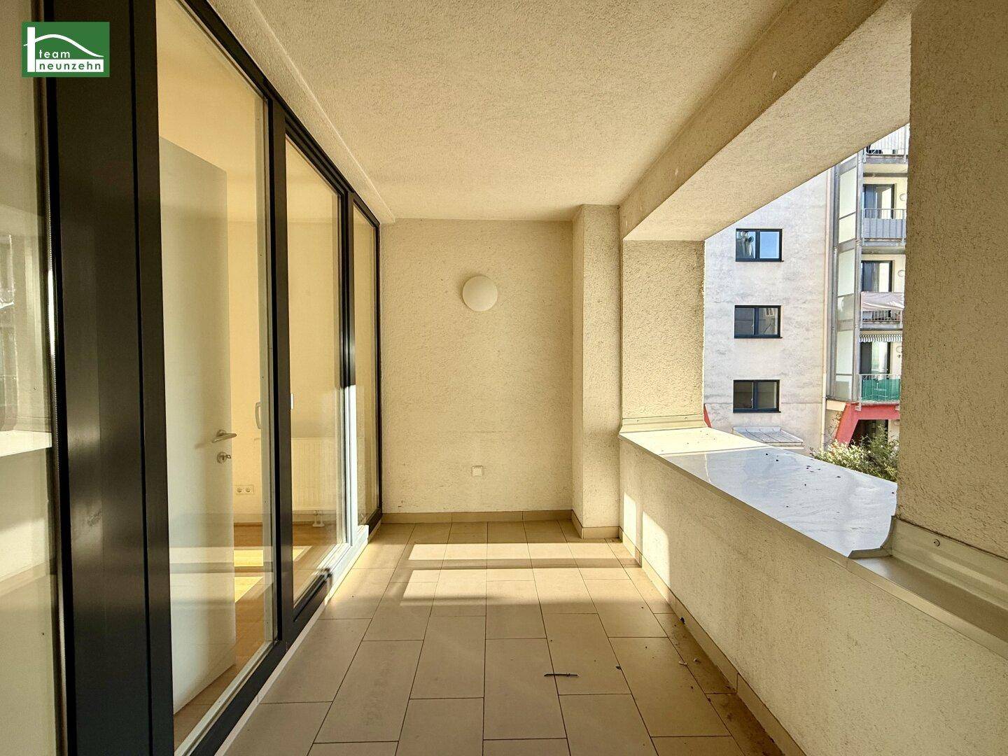 Langer Balkon mit Fliesenboden und großen Glasfronten, die den Innenraum mit Licht versorgen.