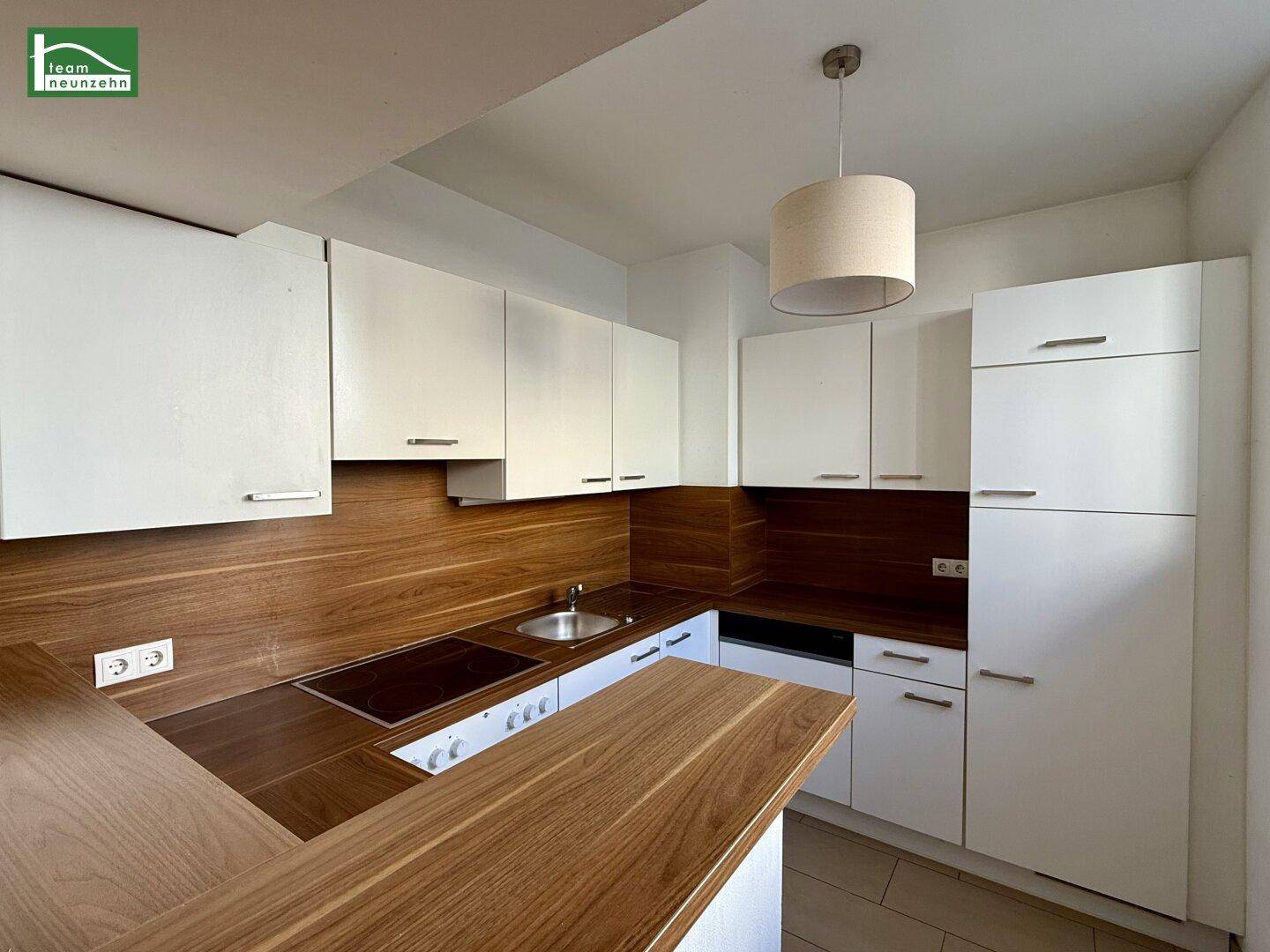 Moderne Einbauküche mit weißen Schränken, Holz-Arbeitsplatten und allen notwendigen Geräten.