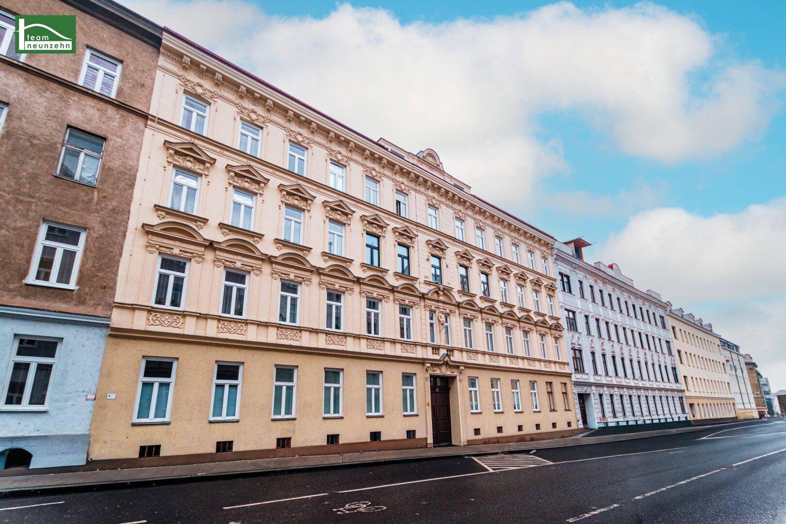 Historisches Gebäude mit reich verzierter Fassade und vielen Fenstern an einer Stadtstraße.