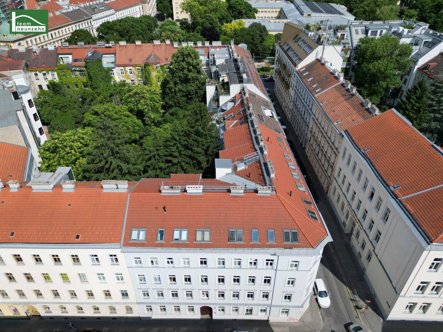 Weitläufige Luftaufnahme eines Wohnviertels mit vielen Gebäuden und grünen Innenhöfen.