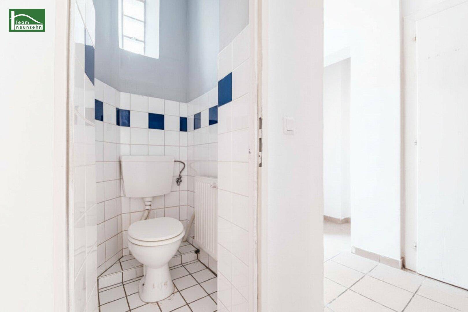 Separate Gästetoilette mit weißen Fliesen und einem kleinen Fenster für Belüftung.