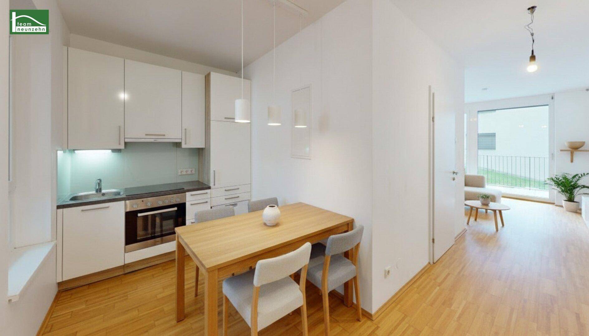 Heller, offener Wohnbereich mit moderner Einbauküche, Esstisch und Zugang zu einem Balkon.