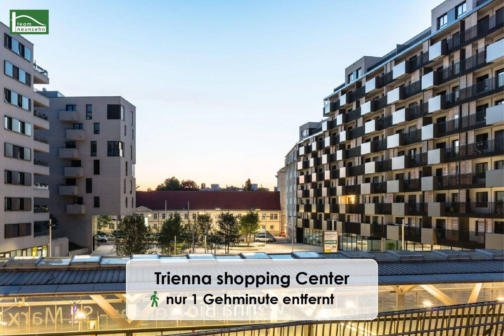 Moderne Wohngebäude mit Balkonen und einer städtischen Infrastruktur im Vordergrund bei Sonnenuntergang.