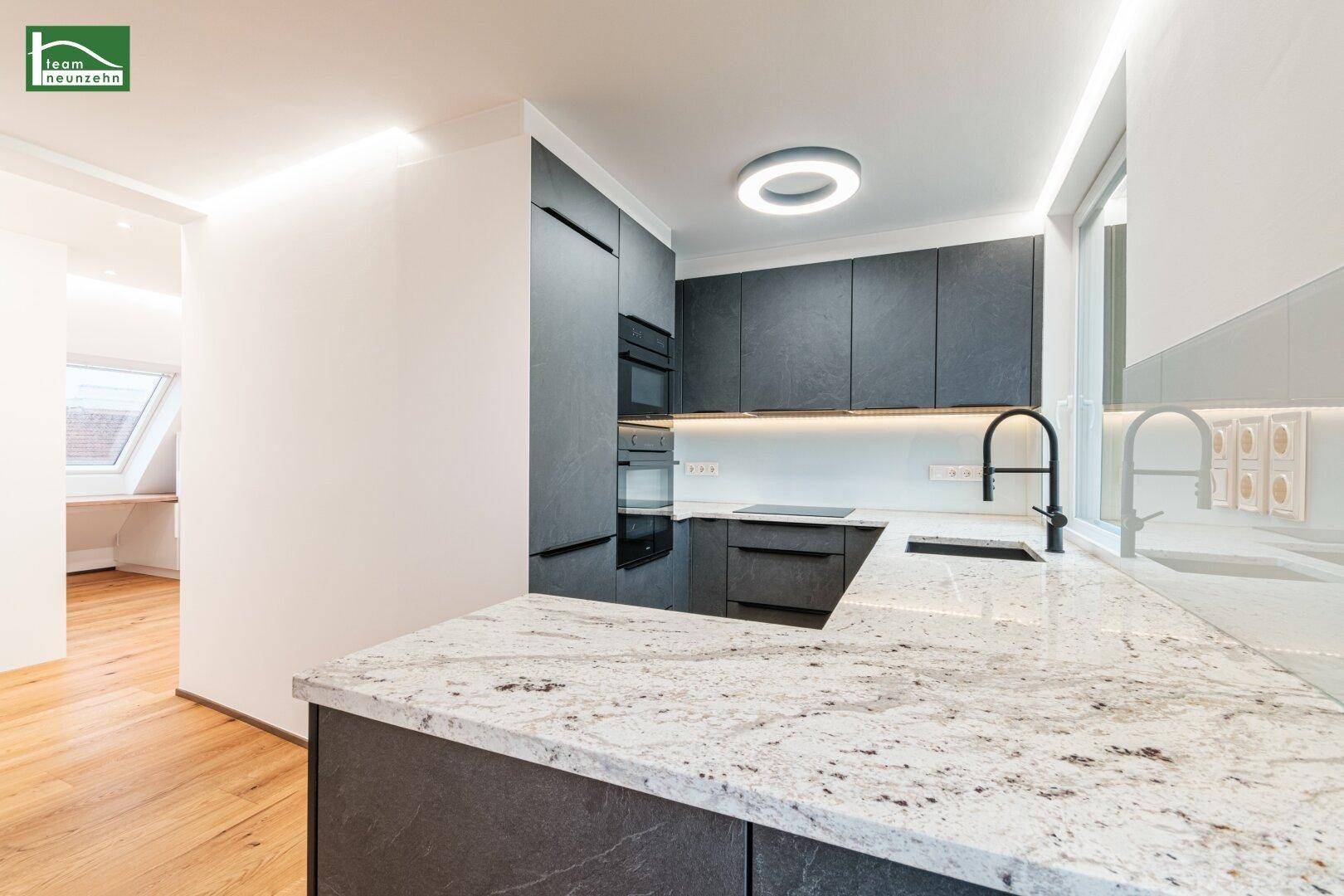 Moderne Küche mit dunklen Schränken, heller Granitarbeitsplatte und integrierten Geräten.
