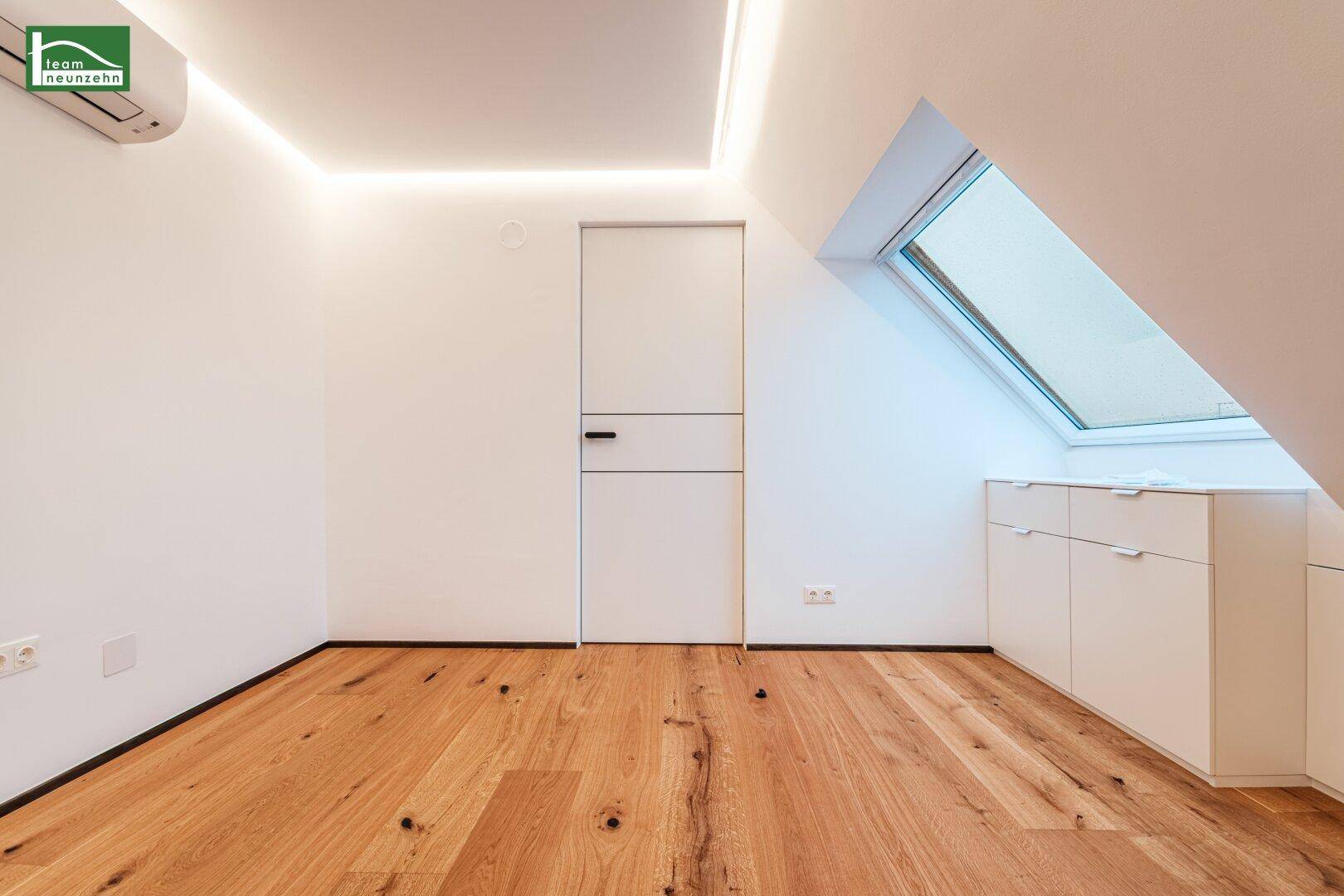 Helles Zimmer mit Dachschräge, großem Dachfenster und integrierten weißen Kommoden.