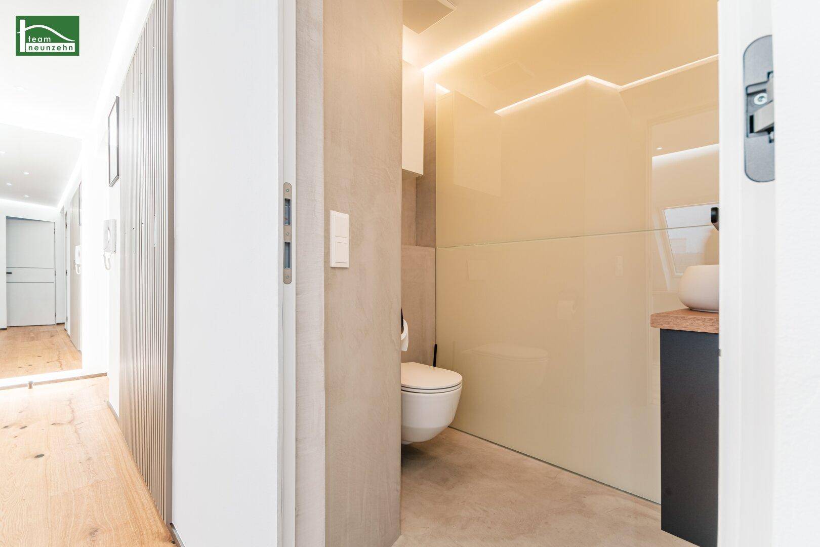 Modernes Gäste-WC mit wandmontierter Toilette und eleganten Fliesen.