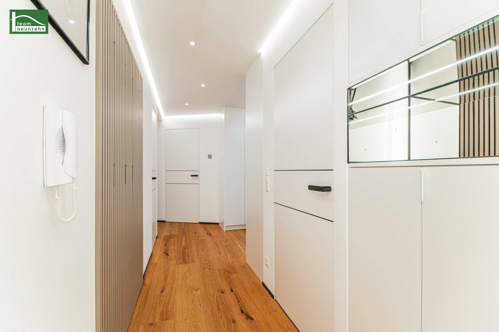 Heller Flur mit Holzboden, modernen Einbauschränken und indirekter Beleuchtung.