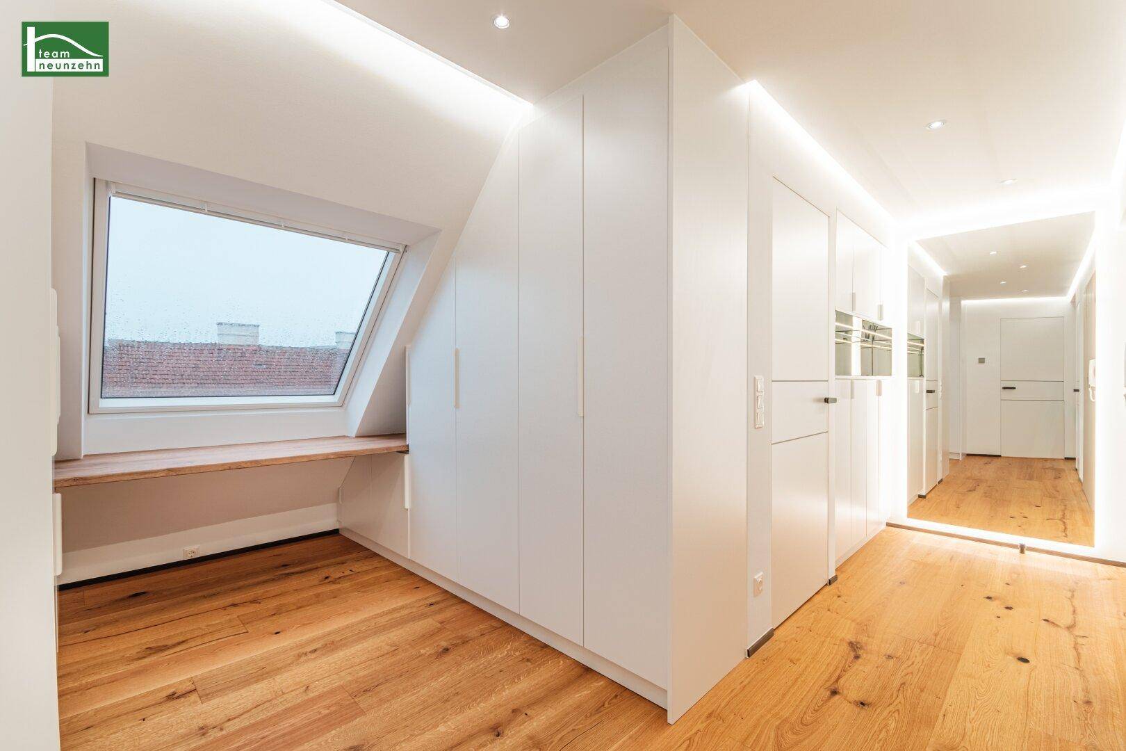 Schlafzimmer mit Dachschräge, großem Dachfenster und integrierten weißen Einbauschränken.
