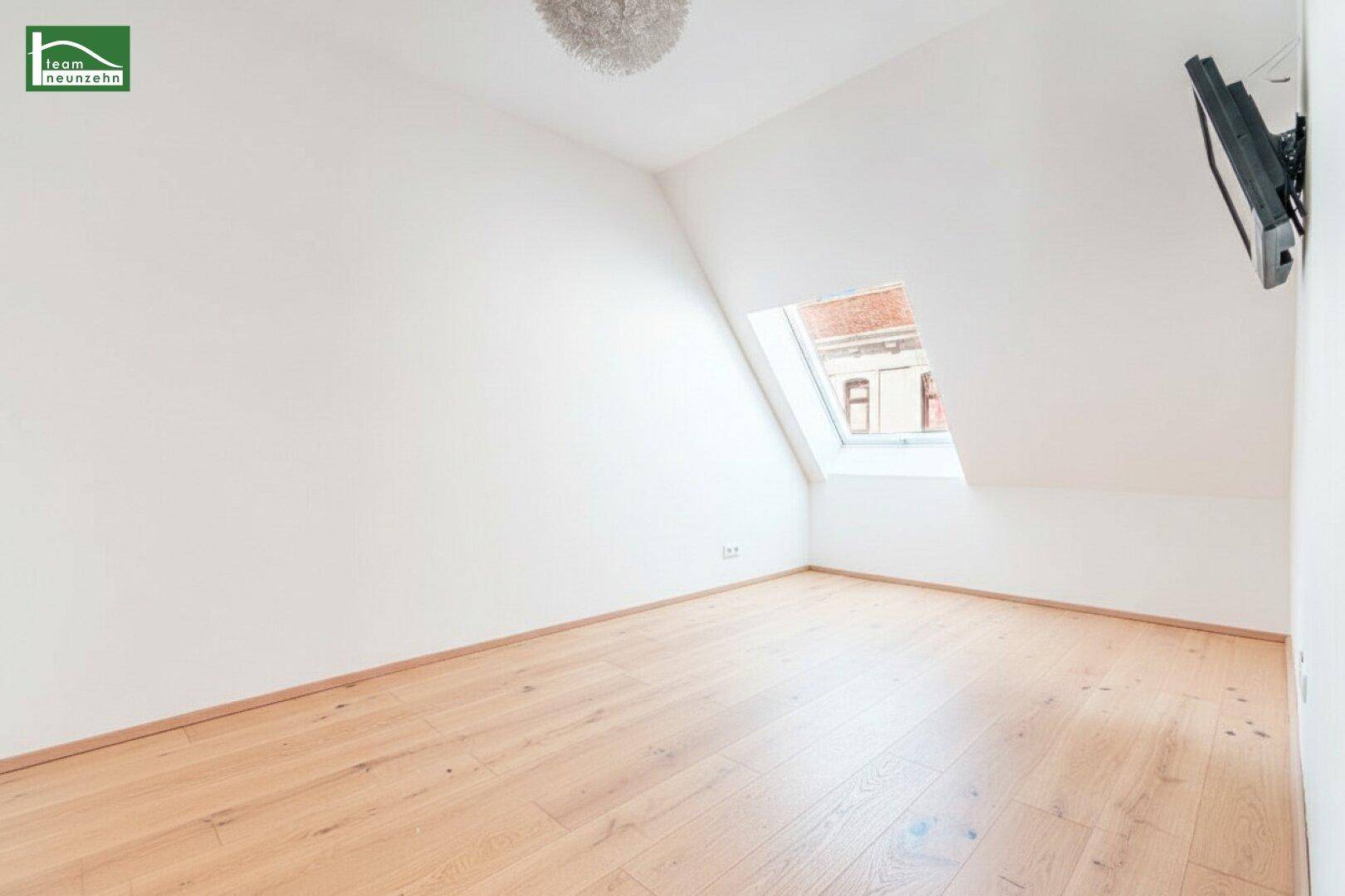 Heller Raum mit Dachschräge, Holzboden und Dachfenster, ideal als Schlafzimmer oder Büro.