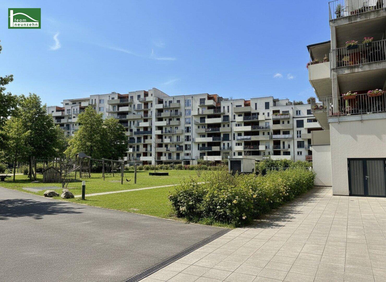 Außenansicht eines modernen Wohnkomplexes mit Grünflächen und Spielplatz.