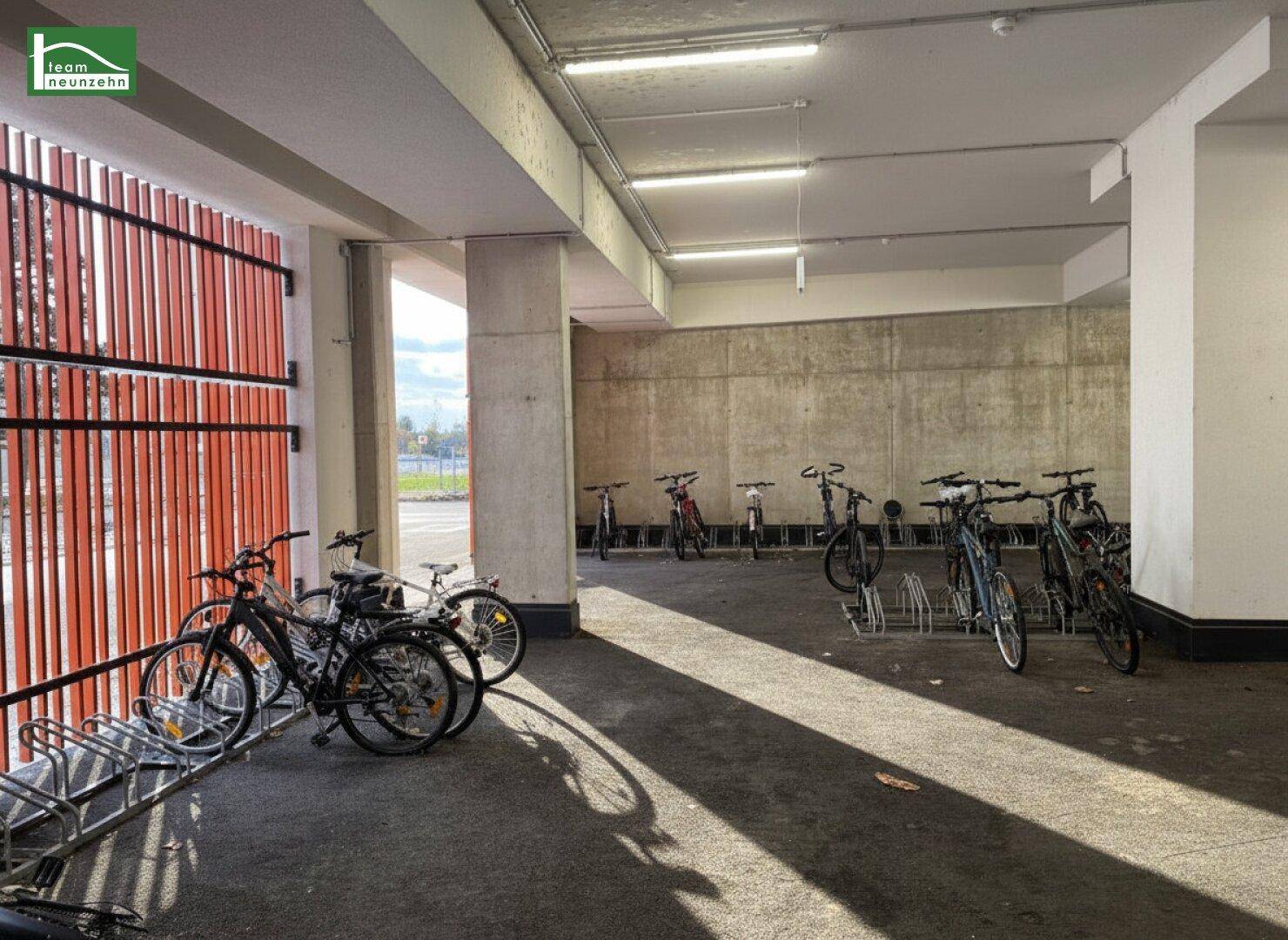 Überdachter Fahrradabstellplatz mit vielen Fahrrädern und Holzlamellen.