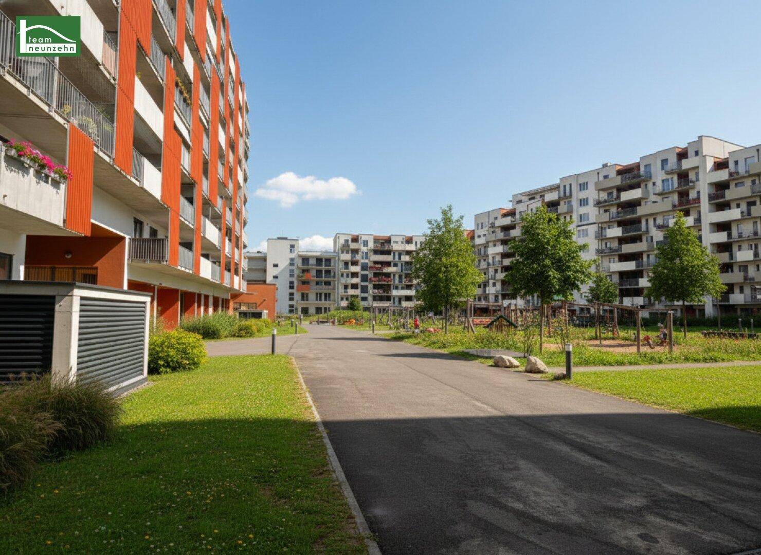 Außenbereich eines Wohnkomplexes mit Wegen, Grünflächen und Gebäuden.