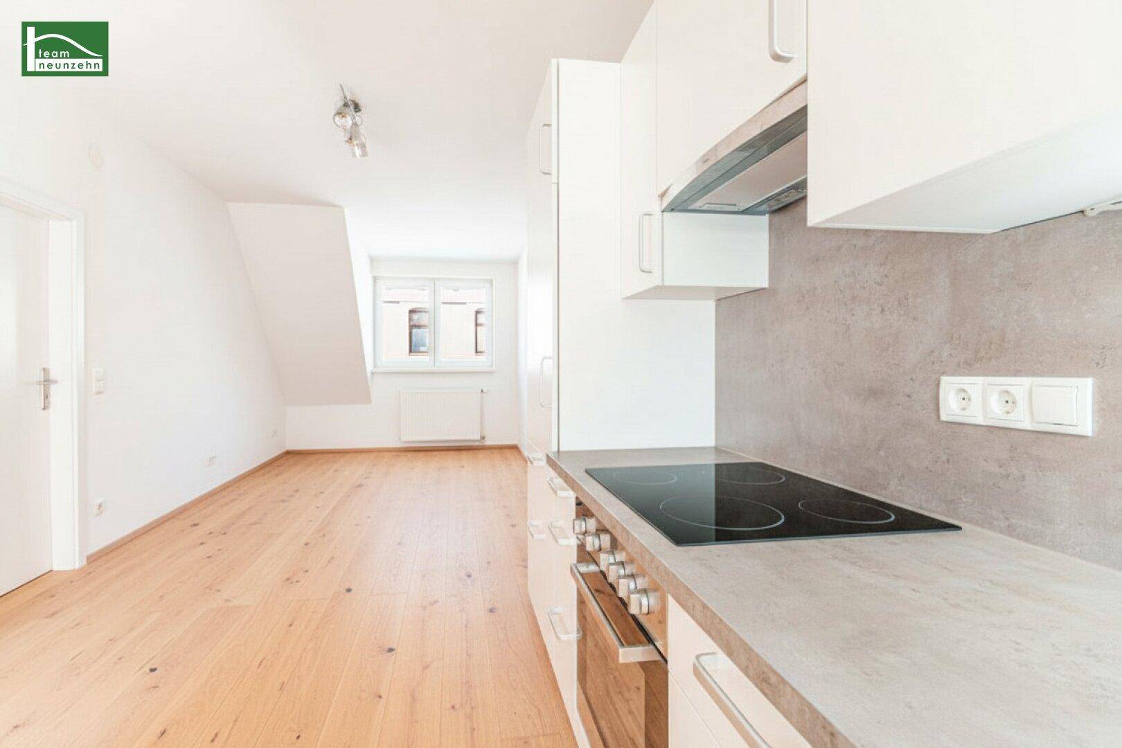 Moderne Küchenzeile mit Induktionskochfeld, Backofen und heller Arbeitsplatte.