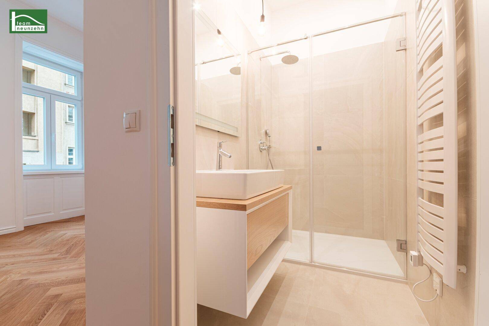 Modernes Badezimmer mit begehbarer Dusche, elegantem Waschtisch und beheiztem Handtuchhalter.