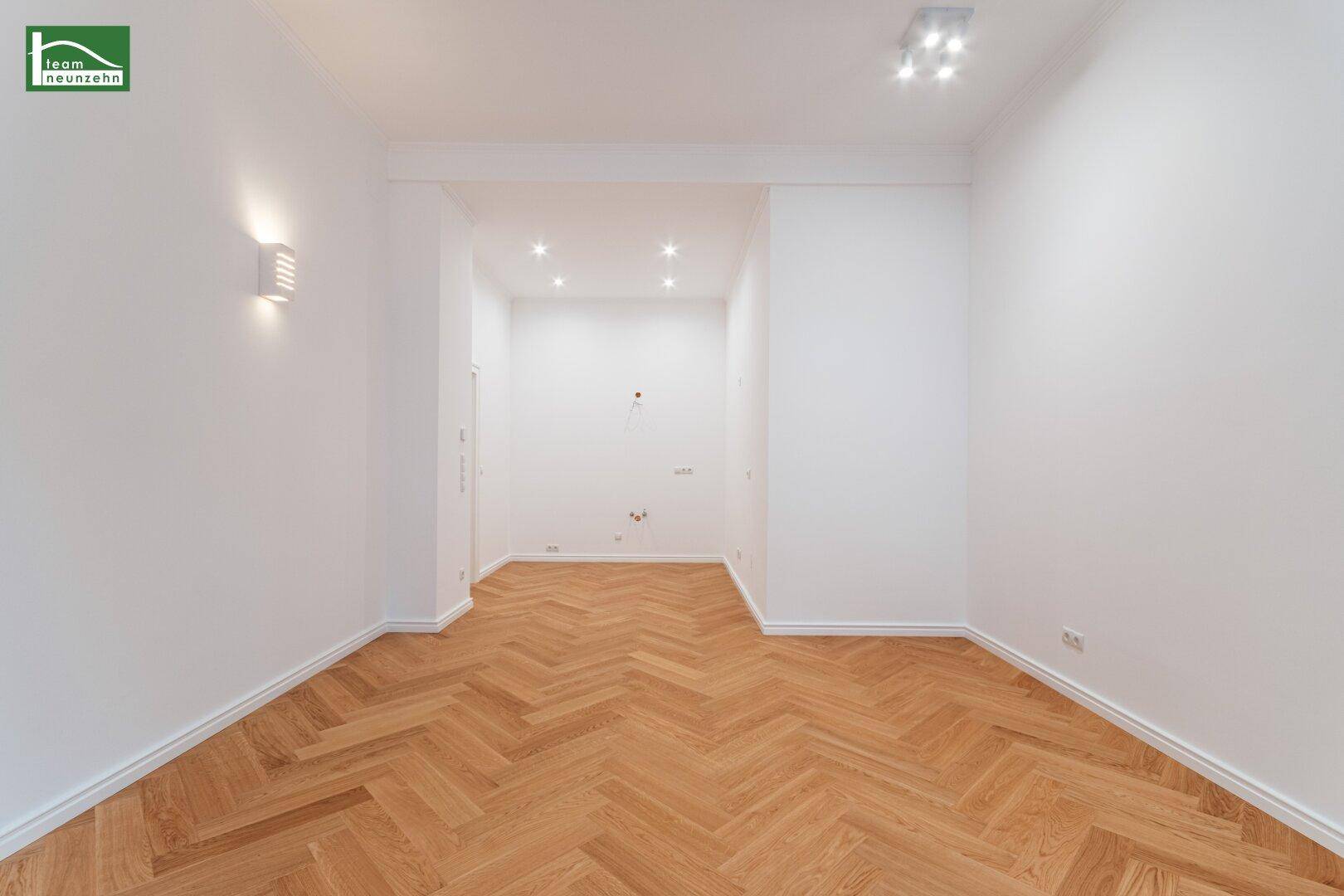 Geräumiges Zimmer mit elegantem Fischgrätparkett und moderner Deckenbeleuchtung, bereit zur individuellen Gestaltung.