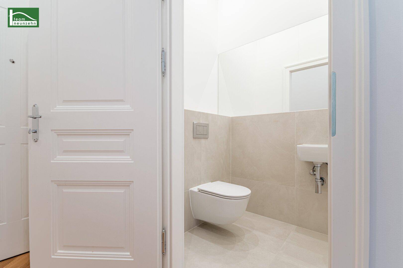 Modernes Gäste-WC mit wandhängendem WC, kleinem Waschbecken und großem Spiegel.