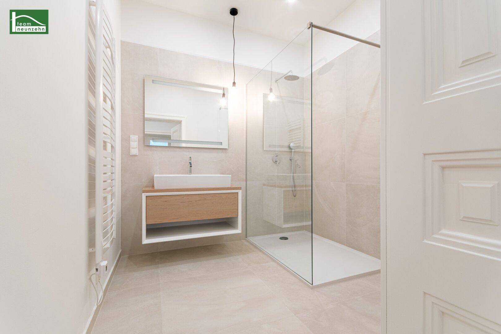 Modernes Badezimmer mit begehbarer Dusche, stilvollem Waschtisch und beheiztem Handtuchhalter.