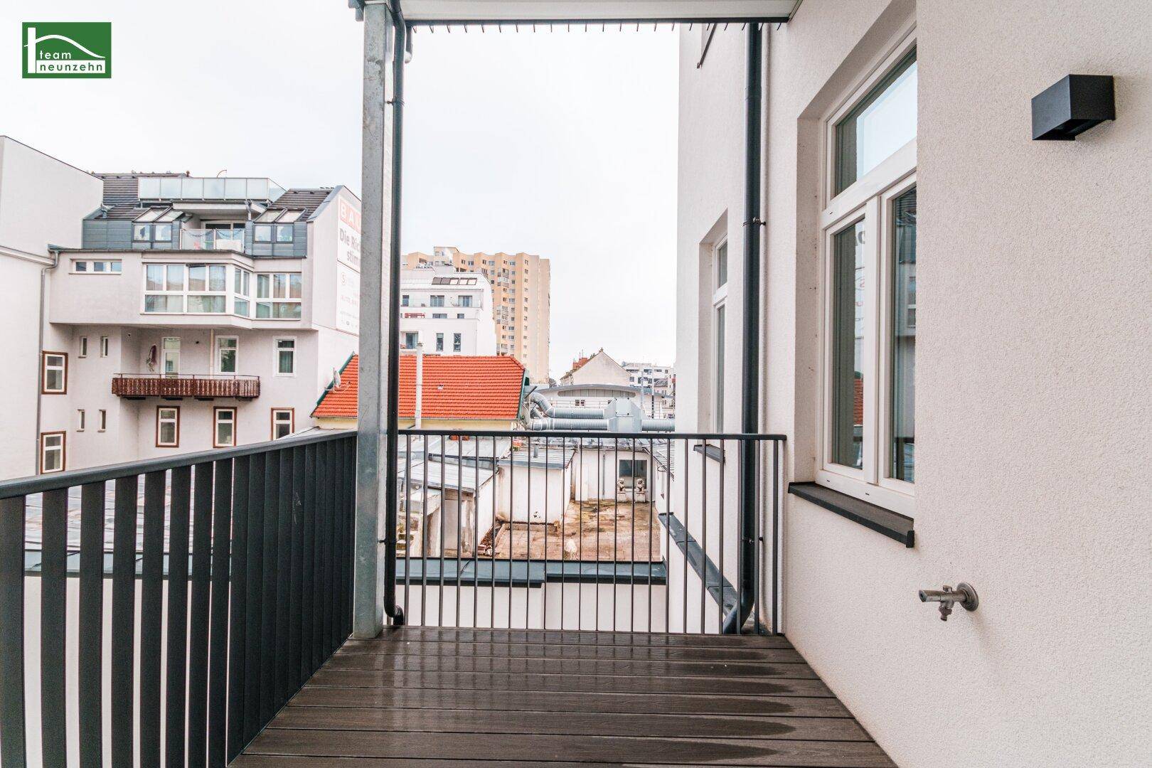 Balkon mit Holzdielenboden und Blick auf die umliegenden Gebäude der Stadt.