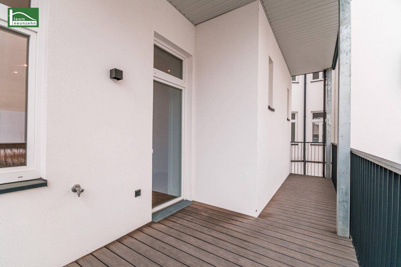 Langer Balkon mit Holzdielen und weißer Fassade, bietet zusätzlichen Platz im Freien.