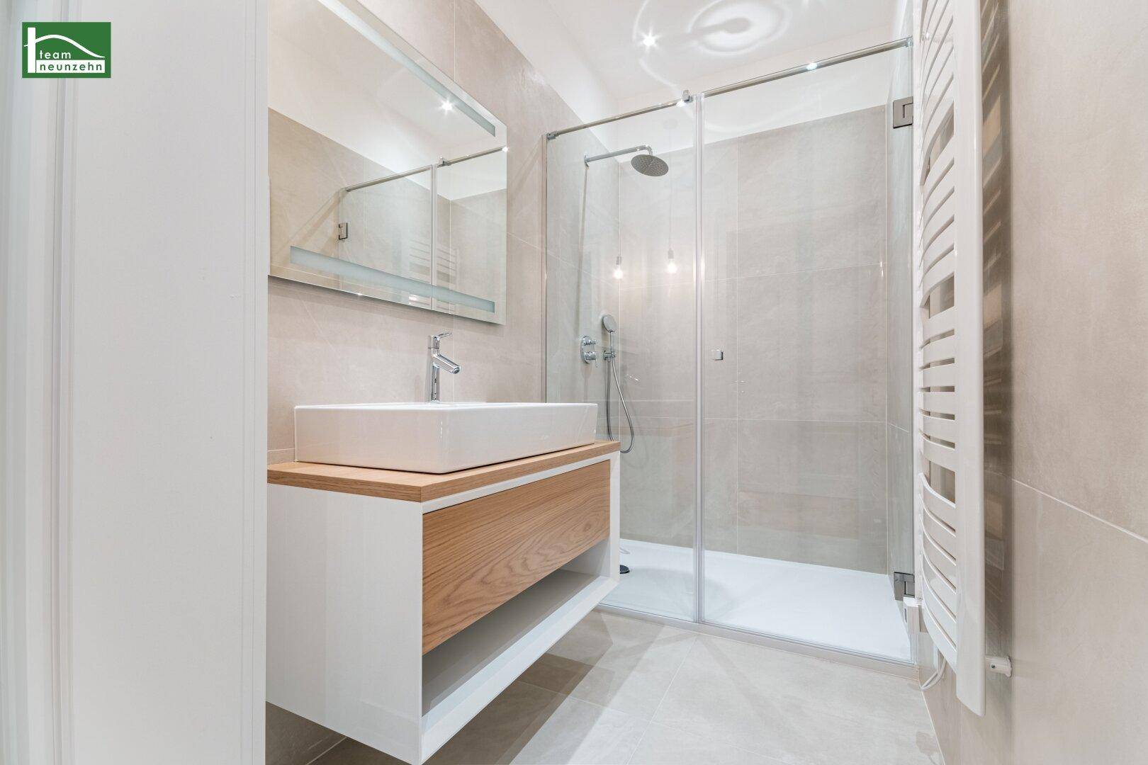 Modernes Badezimmer mit begehbarer Dusche, Waschtisch und beheiztem Handtuchhalter.