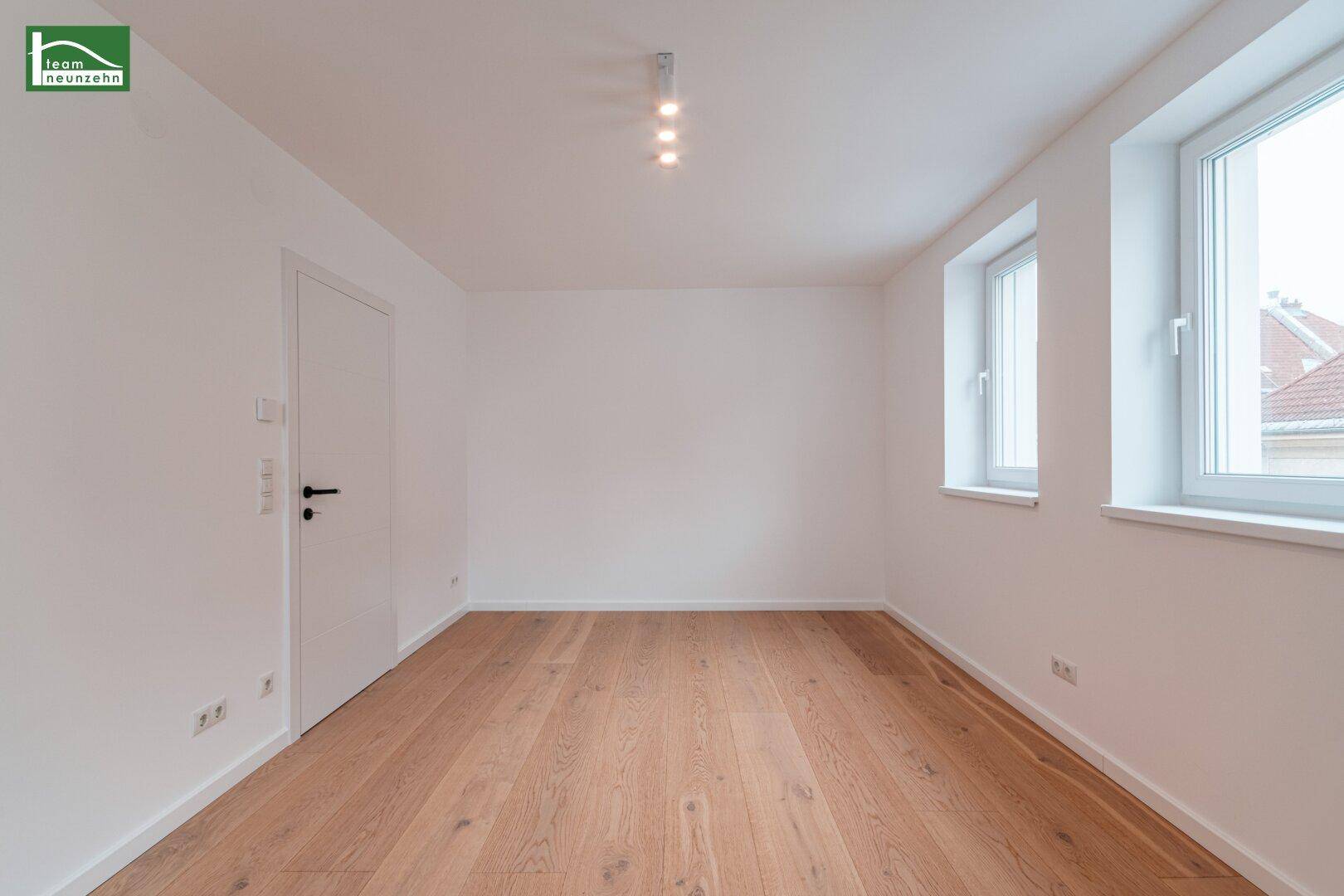 Leerer Raum mit hellem Parkettboden und zwei Fenstern, ideal für ein Schlafzimmer oder Büro.
