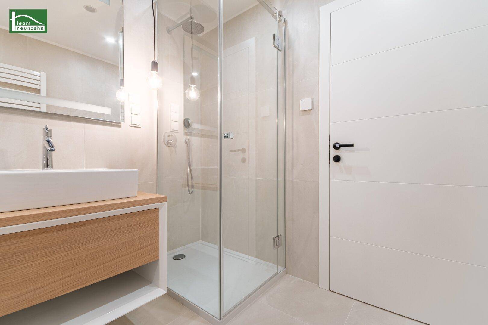 Modernes Badezimmer mit begehbarer Dusche, stilvollem Waschbecken und hellen Fliesen.