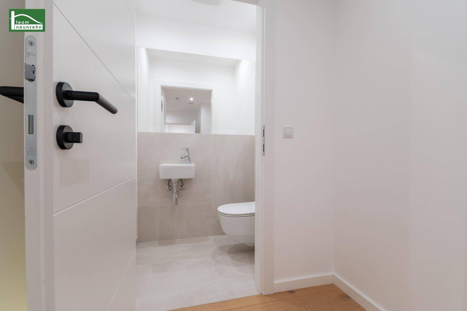 Kleines, modernes Gäste-WC mit wandhängender Toilette und kleinem Handwaschbecken.