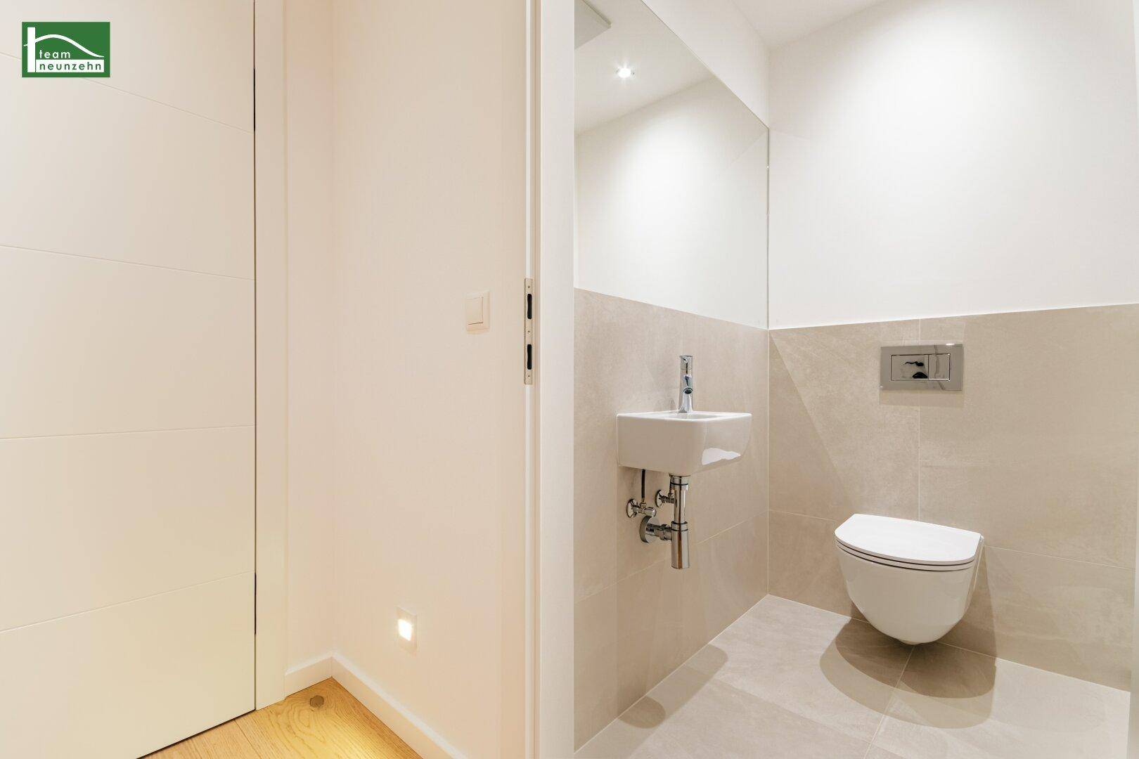 Modernes Gäste-WC mit wandhängender Toilette und kleinem Waschbecken, in hellen Farbtönen gehalten.