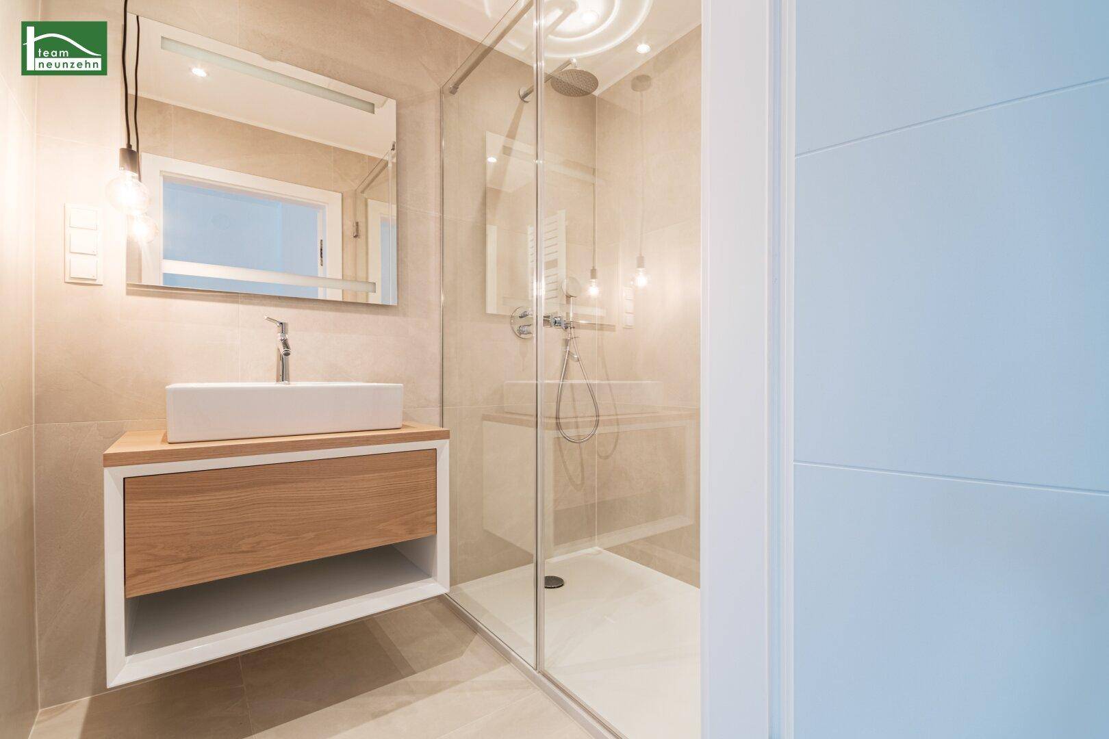Modernes Badezimmer mit begehbarer Dusche, stilvollem Waschtisch und großem Spiegel.