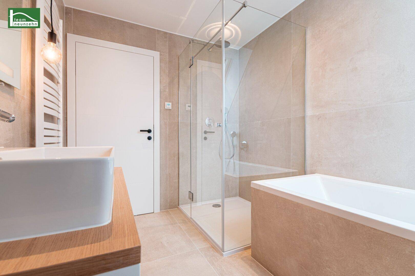 Elegantes Badezimmer mit Badewanne, Glasdusche und beheiztem Handtuchhalter.