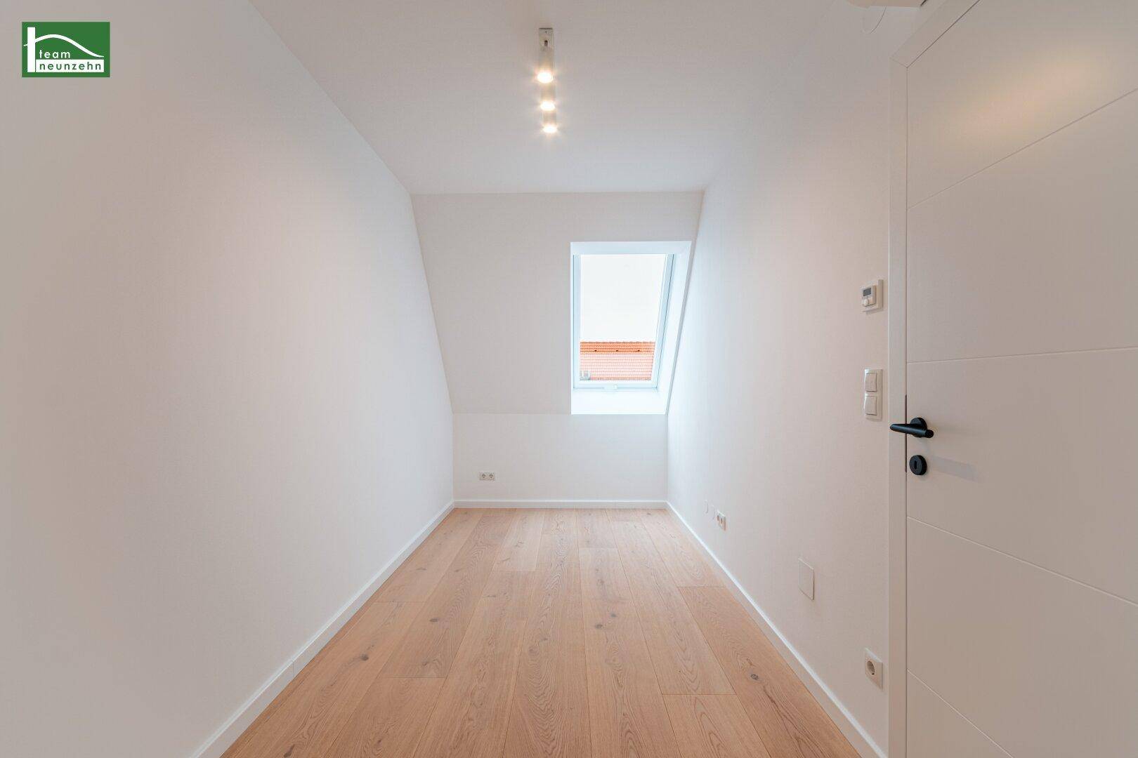 Kleineres Zimmer im Dachgeschoss mit Holzboden und einem einzelnen Dachfenster.