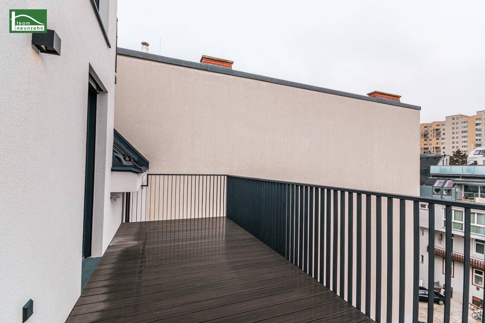 Geräumiger Balkon mit dunklem Bodenbelag und Blick auf die umliegenden Gebäude.