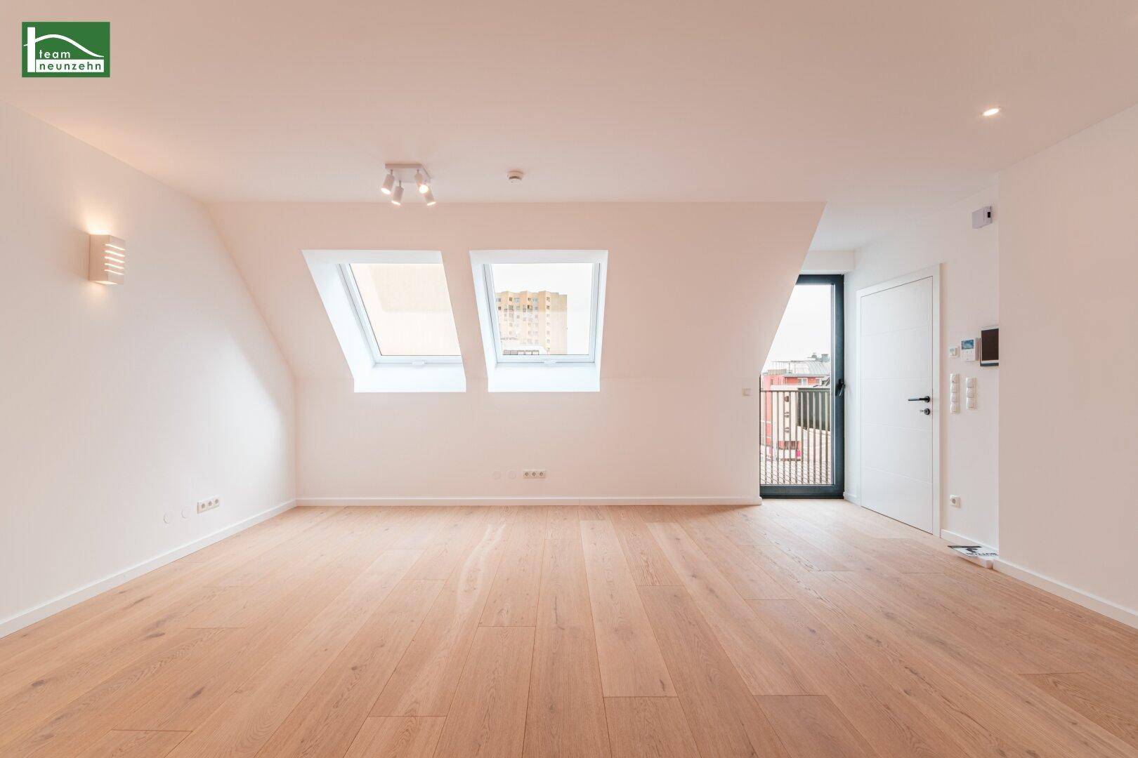 Geräumiges Dachgeschosszimmer mit zwei Dachfenstern und Zugang zu einem Balkon.