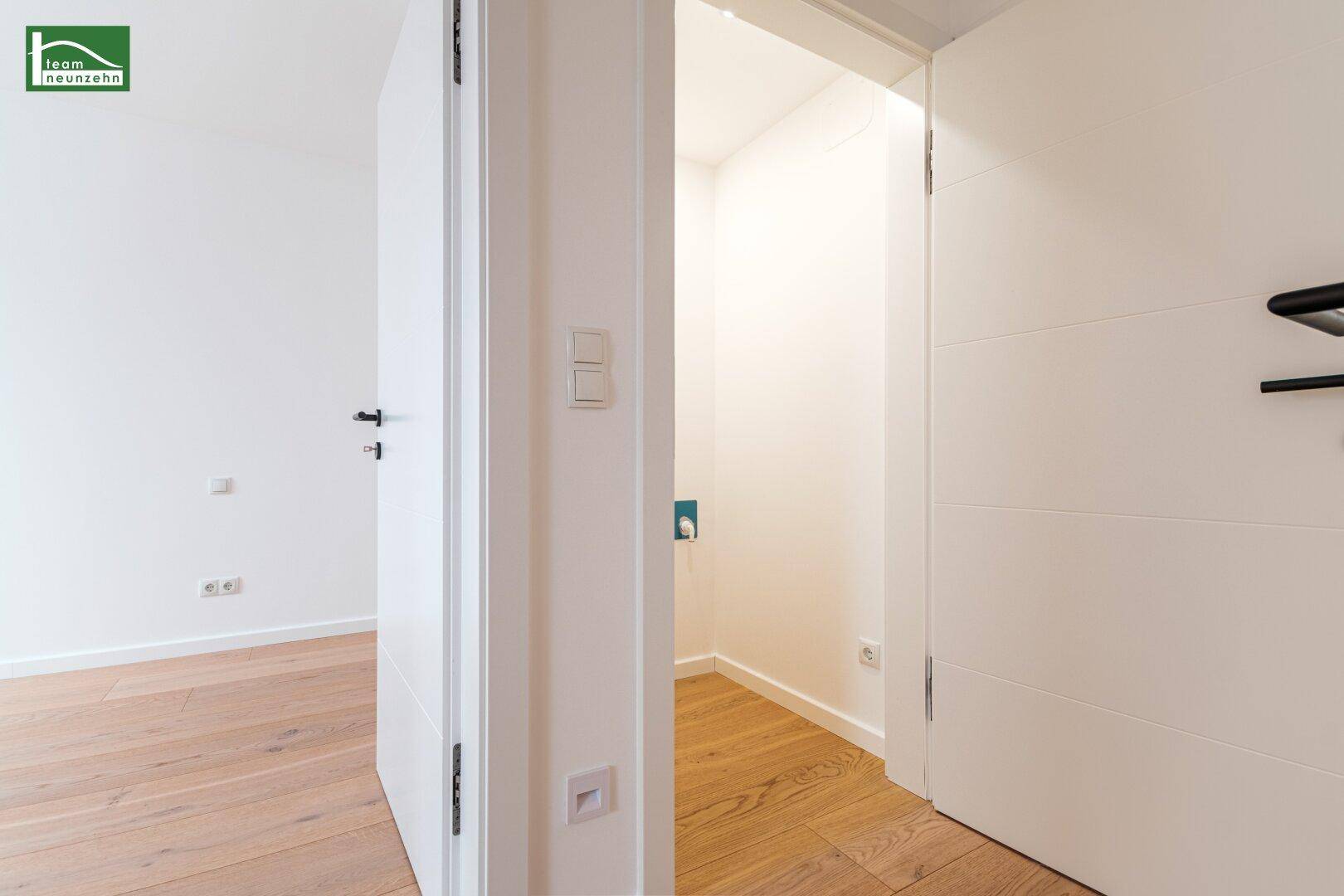 Heller Flur mit Holzboden und Zugang zu einem kleinen Nebenraum.