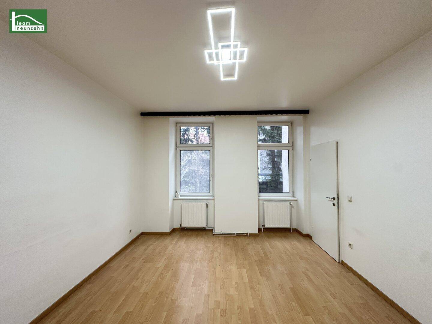 Heller Raum mit Parkettboden und moderner Deckenleuchte, bietet viel Tageslicht.