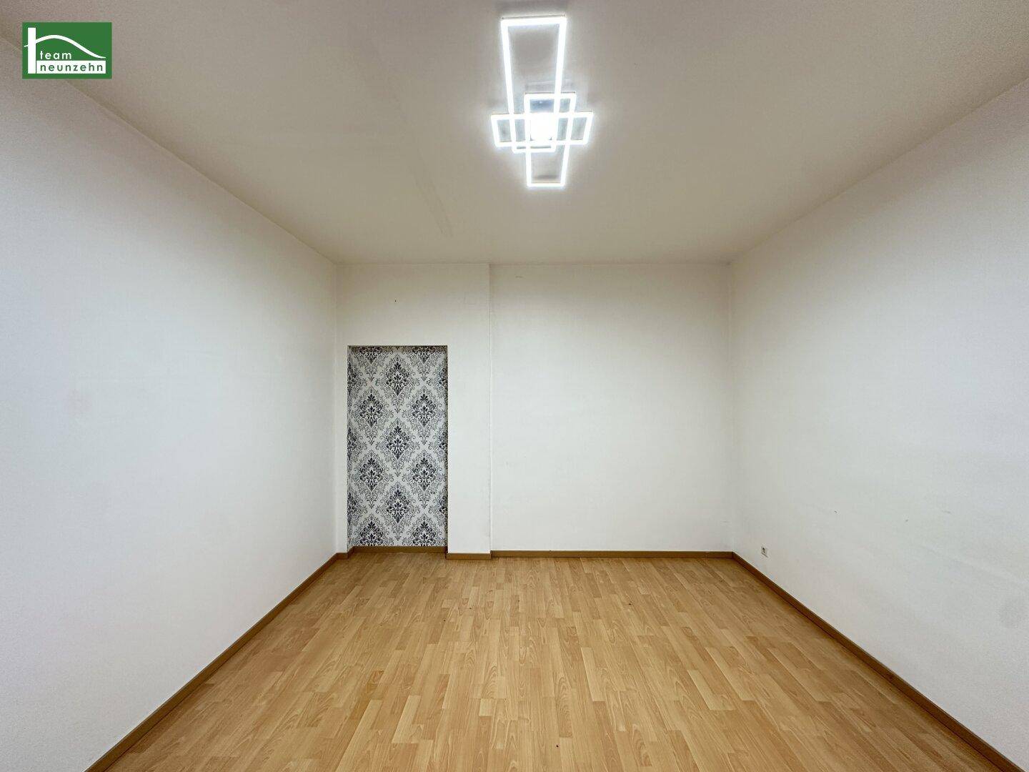 Leerer Raum mit Parkettboden und dekorativer Wandfläche, bereit zur individuellen Gestaltung.