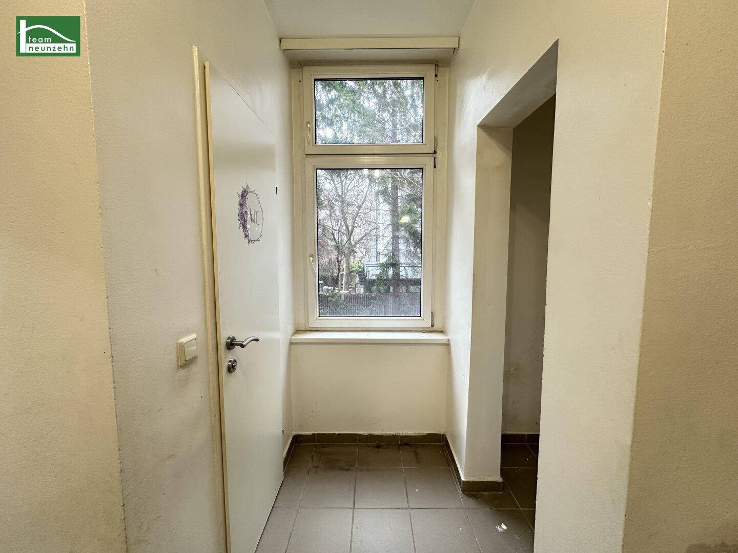 Schmaler Flur mit Fenster und Fliesenboden, bietet Zugang zu anderen Bereichen.