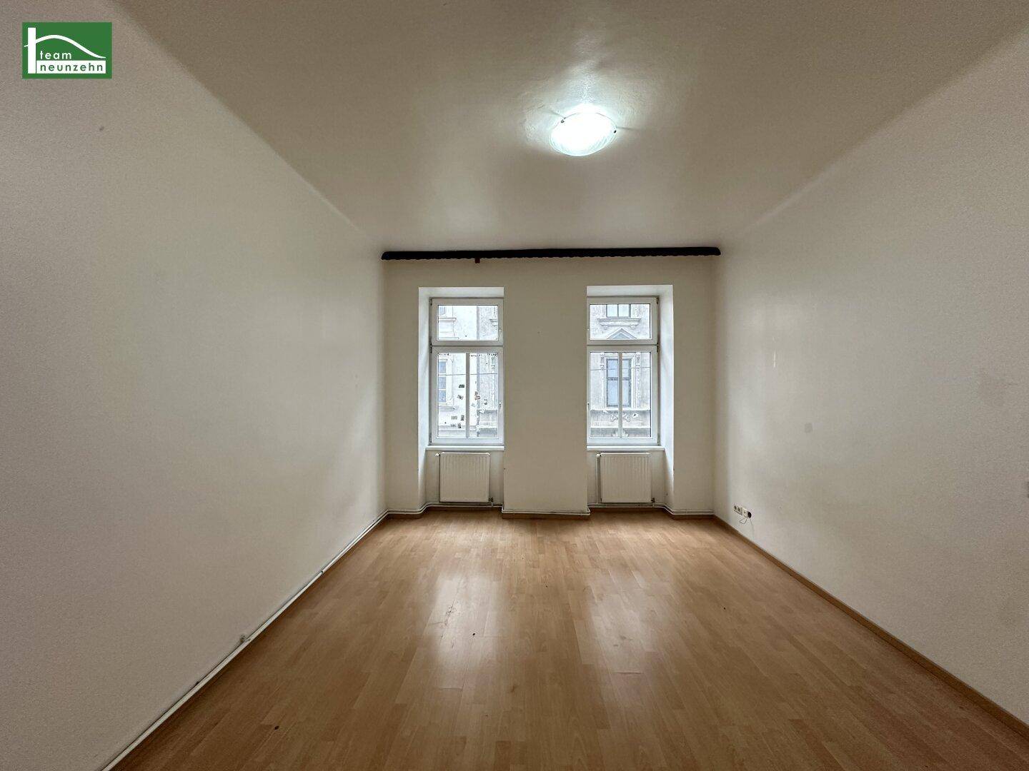 Heller, leerer Raum mit Parkettboden und zwei Fenstern, bereit zur individuellen Gestaltung.