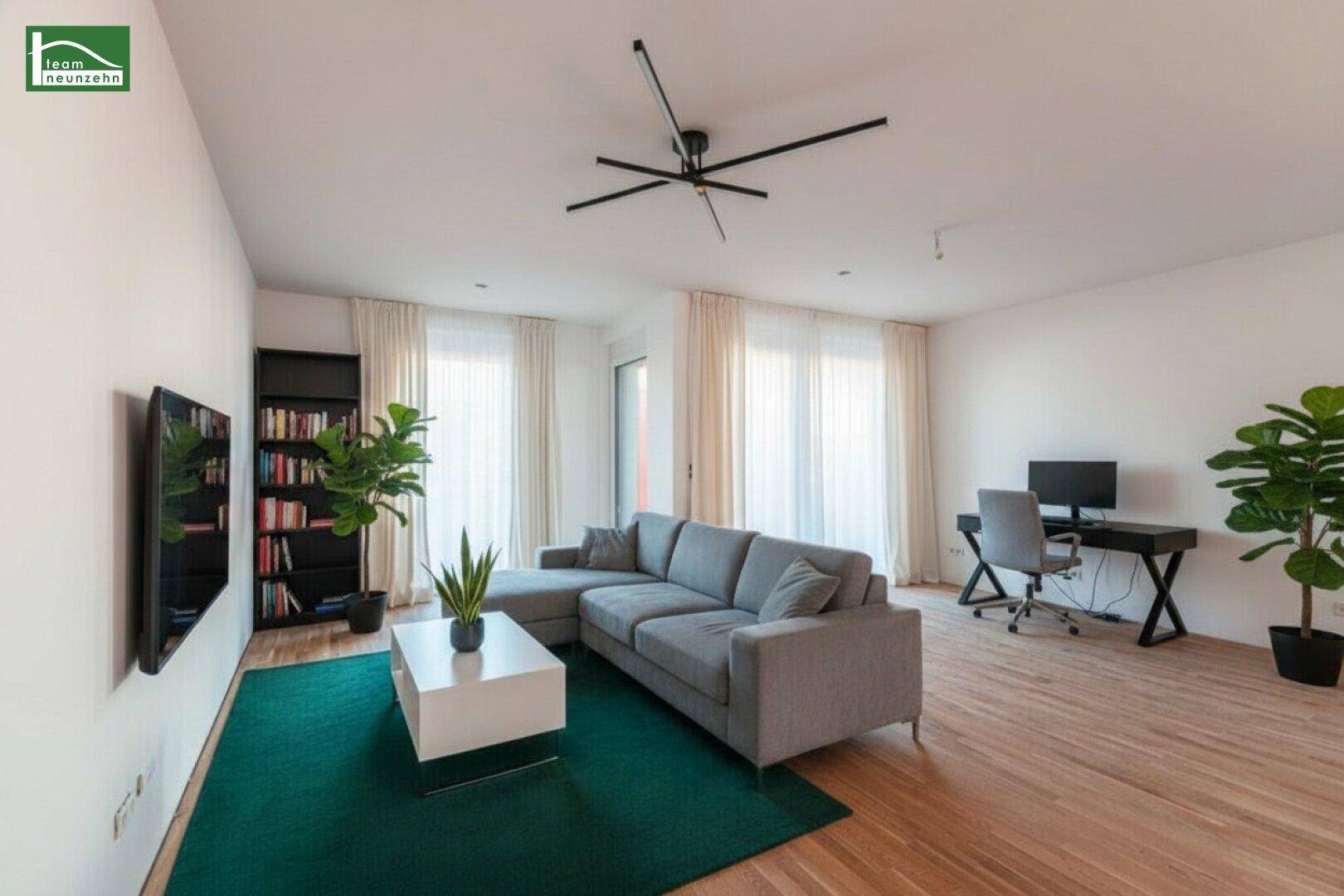 Helles Wohnzimmer mit modernem Sofa, Schreibtischbereich und Holzboden.