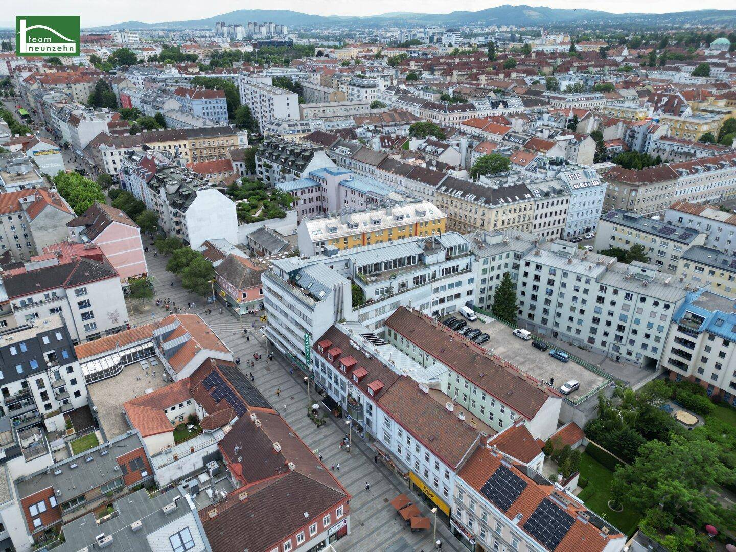 Panoramablick über ein dicht bebautes Stadtgebiet mit Bergen im Hintergrund.