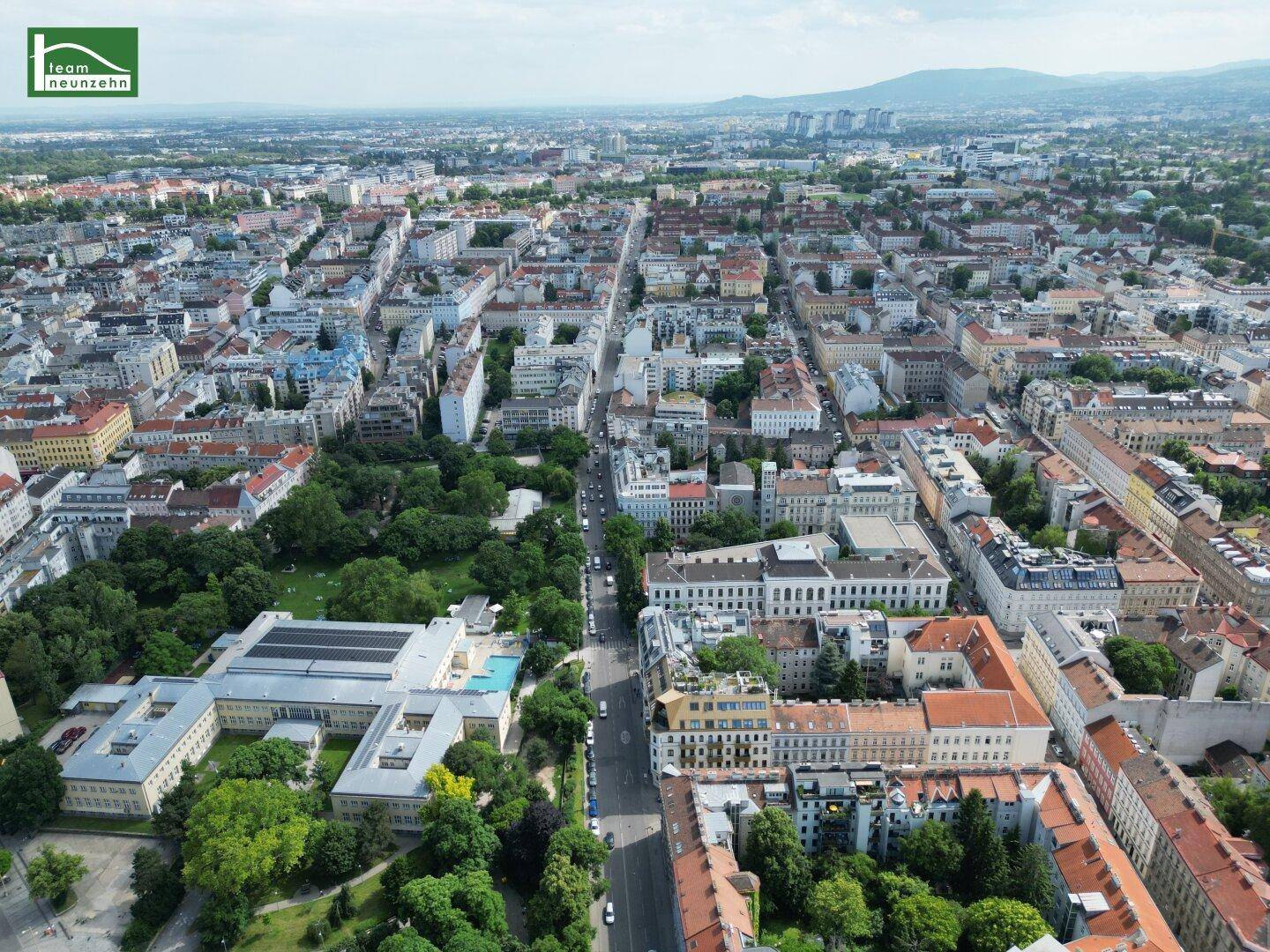 Weitläufige Luftaufnahme einer Stadt mit vielen Gebäuden und grünen Parkanlagen.